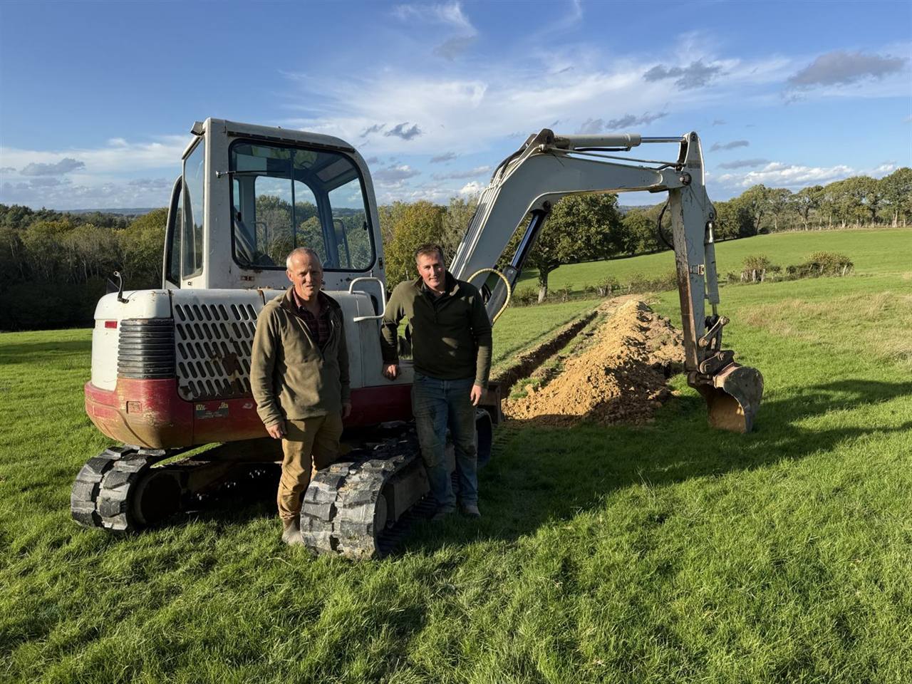 Two members of the Green Septic Solutions team beside an excavator